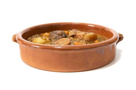 Plato de cabrito guisado tradicional servido en cazuela de barro con patatas