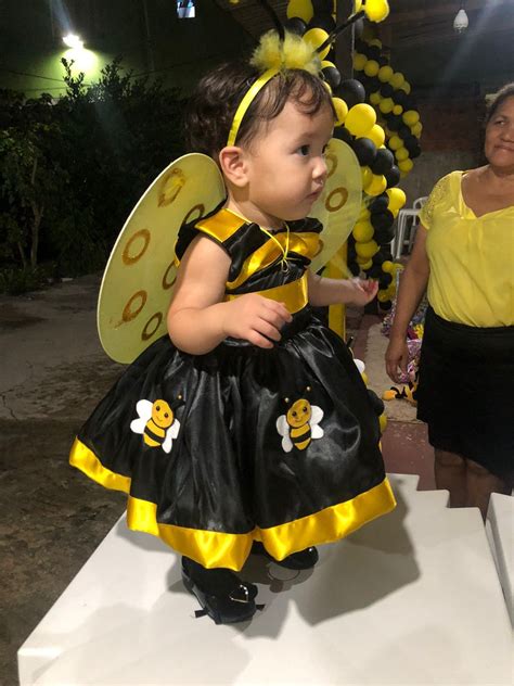 Bebé con un vestido de abejita, fondo de jardín