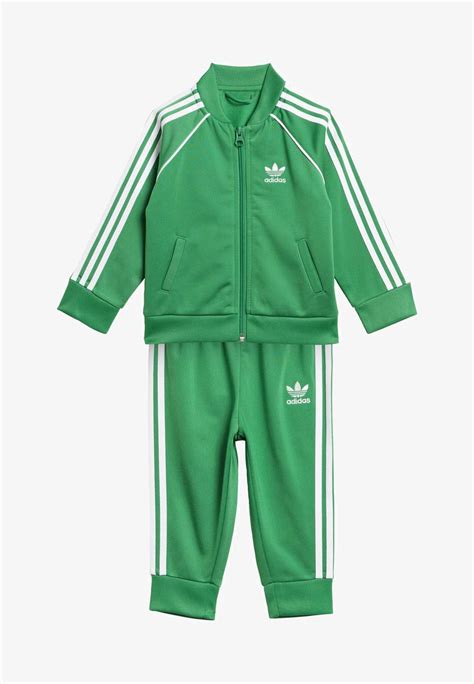 Fotografía de estudio de un niño vistiendo un chándal Adidas de color verde con detalles característicos de la marca.