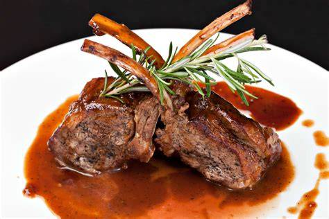 Plato de chuletas de cabrito en salsa de vino con guarnición