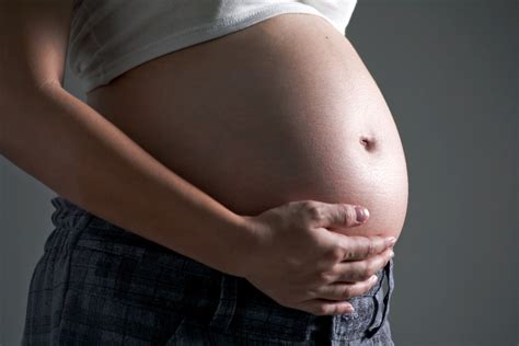 Mujer embarazada durante el proceso de aplicación de tiras de yeso sobre su barriga.