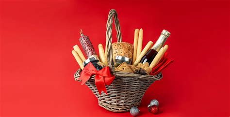 Fotografía de una cesta de Navidad premium que incluye embutidos ibéricos, botellas de vino y dulces tradicionales dispuestos sobre una bandeja de madera