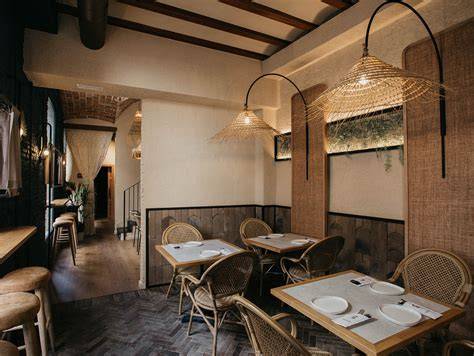 Interior del restaurante con decoración de madera y estilo colonial, mostrando la zona de parrilla abierta y ambiente acogedor