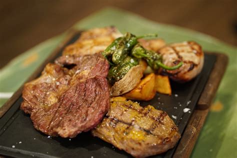Plato de carne a la brasa servido con guarnición y detalle de los bocadillos generosos típicos del local