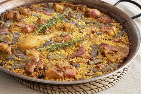 Plato de paella valenciana humeante, croquetas doradas y crujientes, ensaladilla con presentación moderna