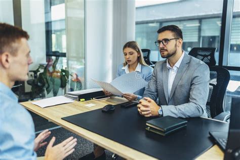 Fotografía de oficina moderna con personal de recursos humanos atendiendo a candidatos en una zona de entrevistas.