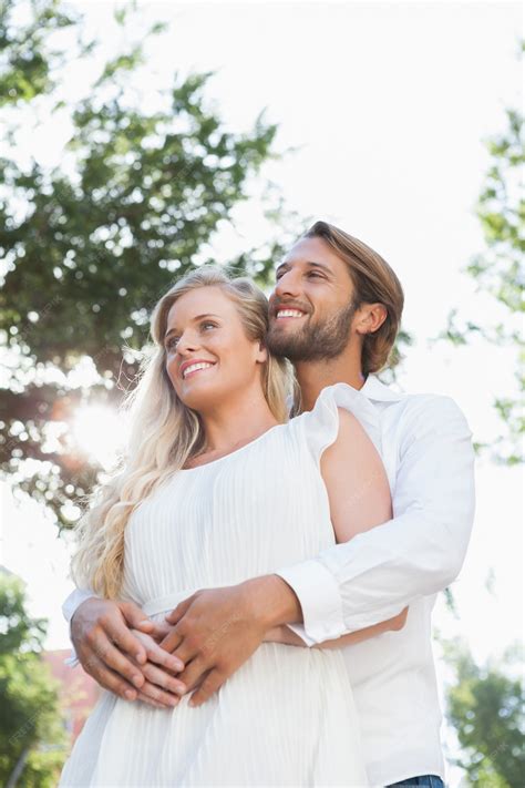 Pareja sonriendo y abrazándose al amanecer