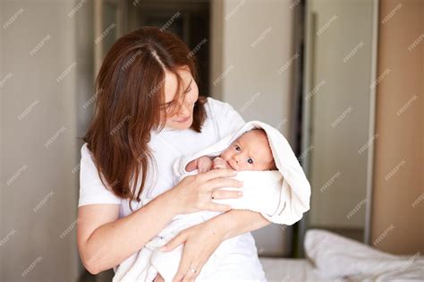 Imagen de una madre joven sosteniendo a su bebé recién nacido con ternura.