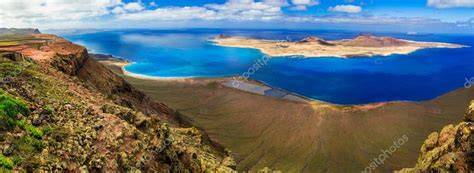 Vista panorámica de Lanzarote mostrando su paisaje volcánico contrastando con el azul del océano.