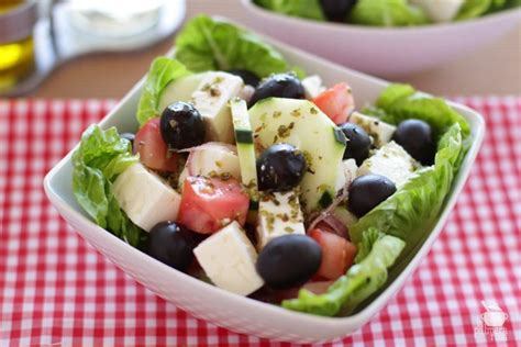 Plato de ensalada griega con queso feta desmenuzado y aceitunas