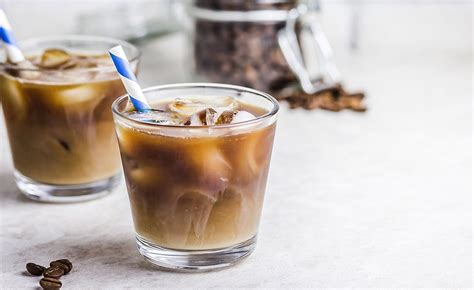 Vaso de café frío con leche, cubitos de hielo y una pajita