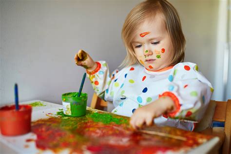 Niño de 18 meses pintando con los dedos en un caballete.