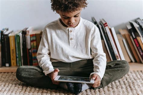 Niño en una biblioteca usando una tablet para buscar información, destacando la alfabetización digital