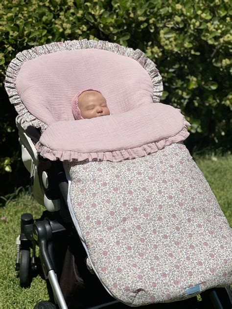 Esquema de un saco para silla de bebé con sus ranuras de arnés y cremalleras