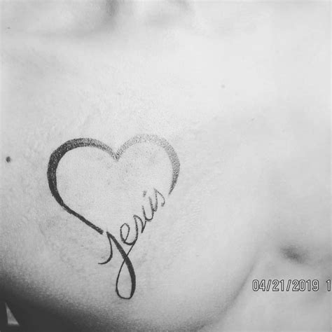 Esquema de diseño de tatuaje que combina tipografía caligráfica para el nombre Jesús con la representación minimalista de un chupete en el antebrazo.