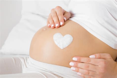 Foto temática de una barriga de embarazada con el ombligo sobresalido y algunas estrías