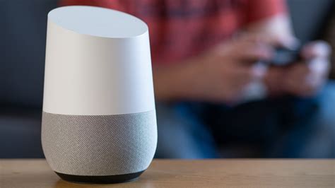 Foto de un Google Home conectado al WiFi junto a un smartphone con la app de Google Home abierta
