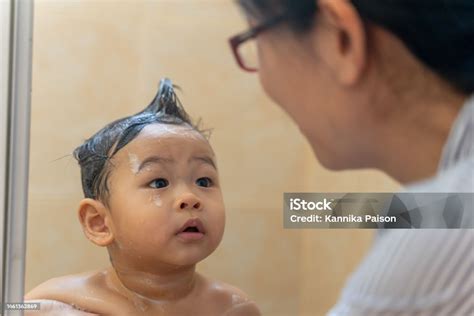 Foto de padre o madre lavando suavemente el cabello de un bebé en la bañera
