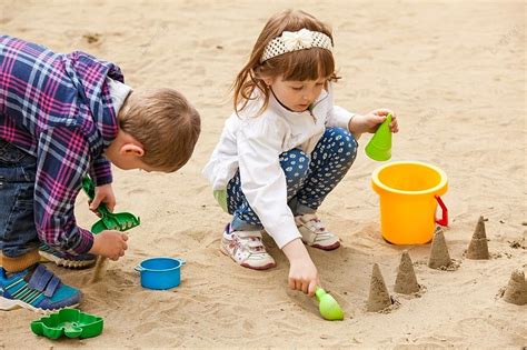 niños jugando en un arenero con cubos y palas