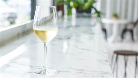 Copa de vino blanco pálido con reflejos verdosos.