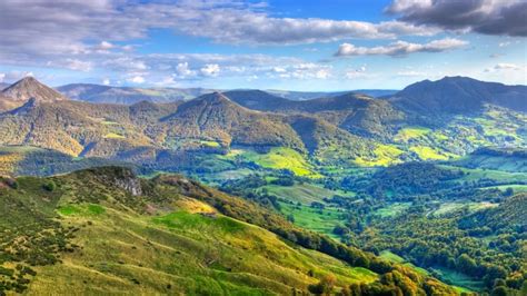 Paisaje montañoso de la región de Auvernia en Francia con pastos verdes y colinas, evocando el ambiente bucólico de la obra