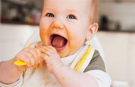 Bebé comiendo papilla de frutas en su silla alta