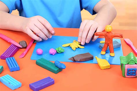 Manos de un niño moldeando plastilina casera de colores con diferentes utensilios como rodillos y cortadores