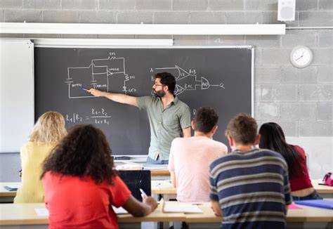 Foto de un profesor en un aula explicando un concepto en la pizarra mientras los estudiantes observan atentamente