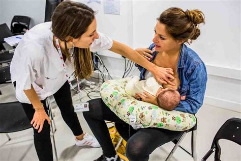 Fotografía de una enfermera o matrona experta en lactancia interactuando con una madre y su bebé en un entorno de grupo