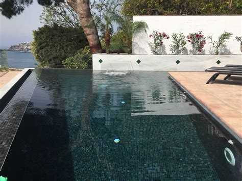Fotografía de una piscina con gresite negro y agua oscura