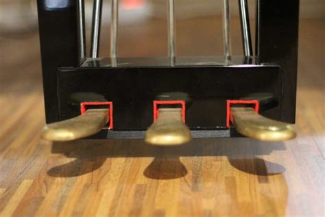 Primer plano de los pedales de un piano, destacando el pedal de sustain