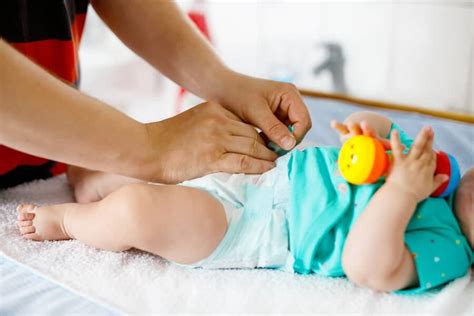Foto de una mano de adulto cambiando el pañal de un bebé, mostrando la limpieza adecuada.