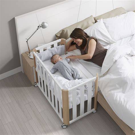Bebé durmiendo plácidamente en una minicuna de colecho junto a la cama de los padres