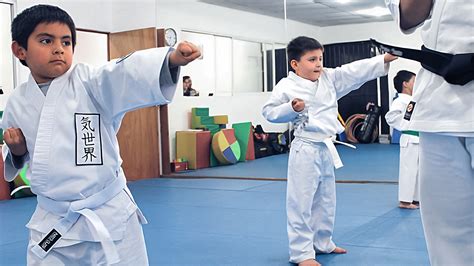 Foto de niños pequeños (entre 3 y 6 años) practicando Judo o Karate en un tatami, con un instructor.