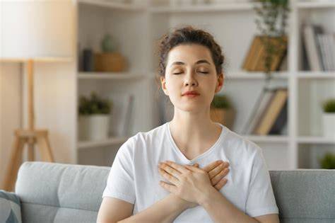 Mujer embarazada meditando con las manos en el pecho, en una pose de calma