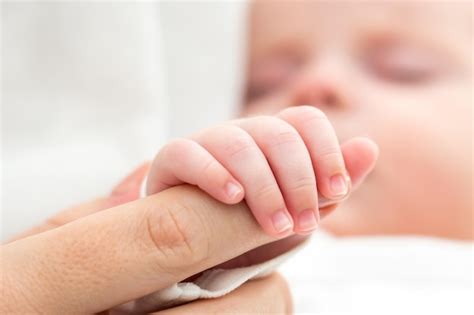 Imagen de una mano de bebé prematuro agarrando un dedo de adulto, simbolizando fragilidad y apoyo