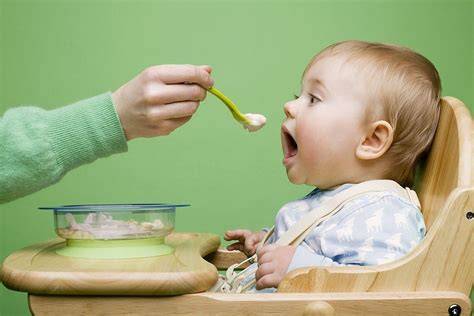 Bebé comiendo papilla de cereales, con padres supervisando