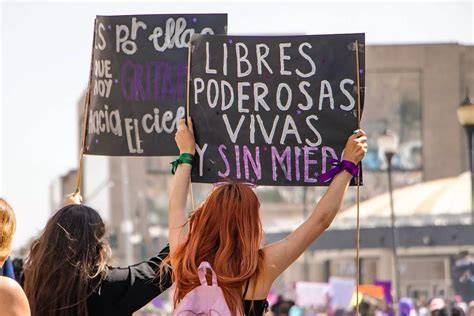 Mujer levantando el puño en una marcha por los derechos de las mujeres, rodeada de otras manifestantes