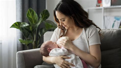 Bebé usando chupete con su madre amamantando al fondo