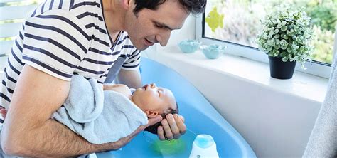 Fotografía de padres interactuando con su recién nacido durante el baño en la unidad neonatal.