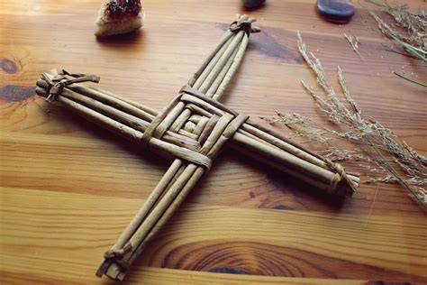 Ilustración de una cruz de Brigid tradicional tejida en paja y velas encendidas como símbolo de purificación.
